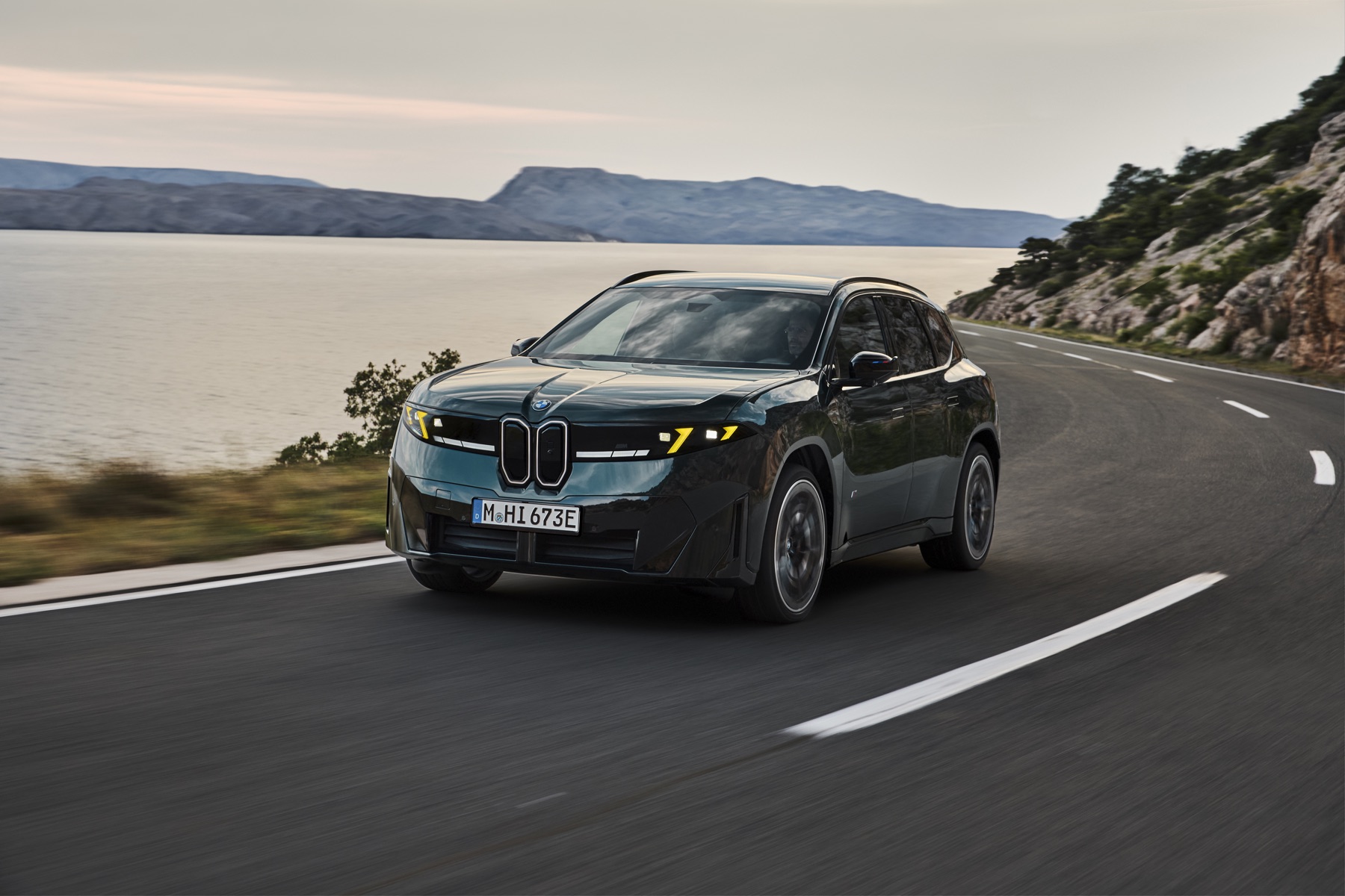 BMW iX3 M60 xDrive driving through a bend on a coastal road